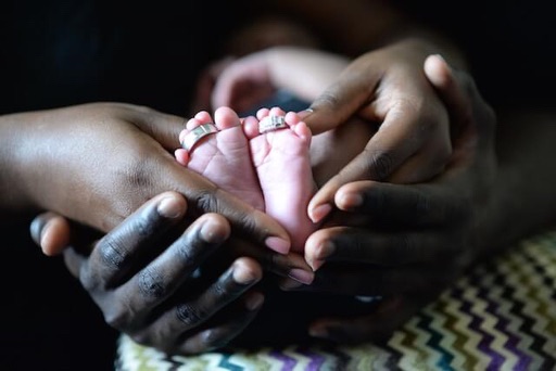 parents hands cradling baby feet